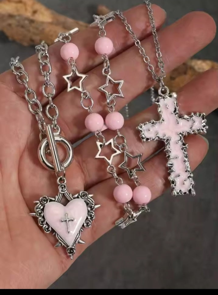 Close up of pink gothic cross heart and star necklace set