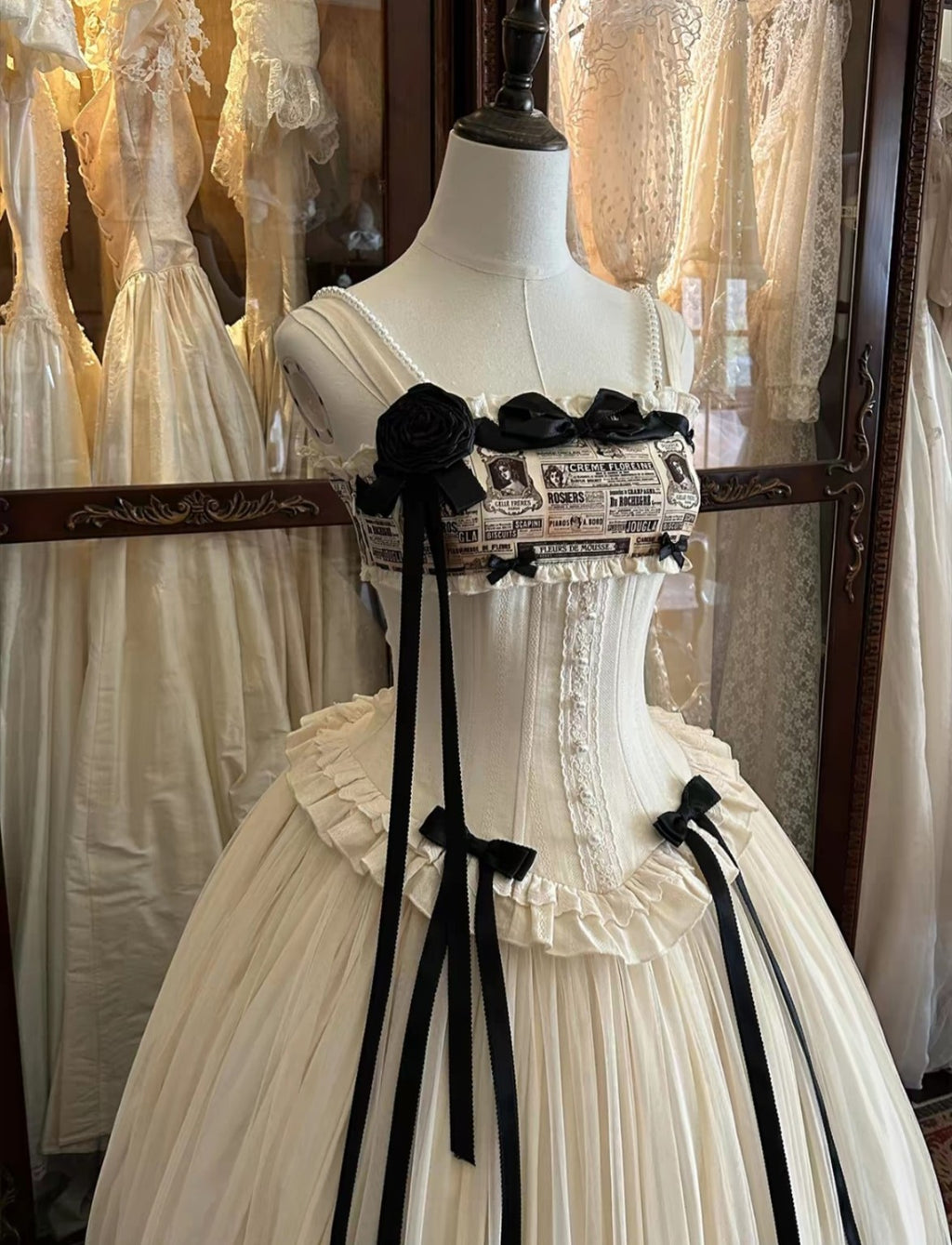 Close up cream Lolita bodice with black bows and vintage newspaper print