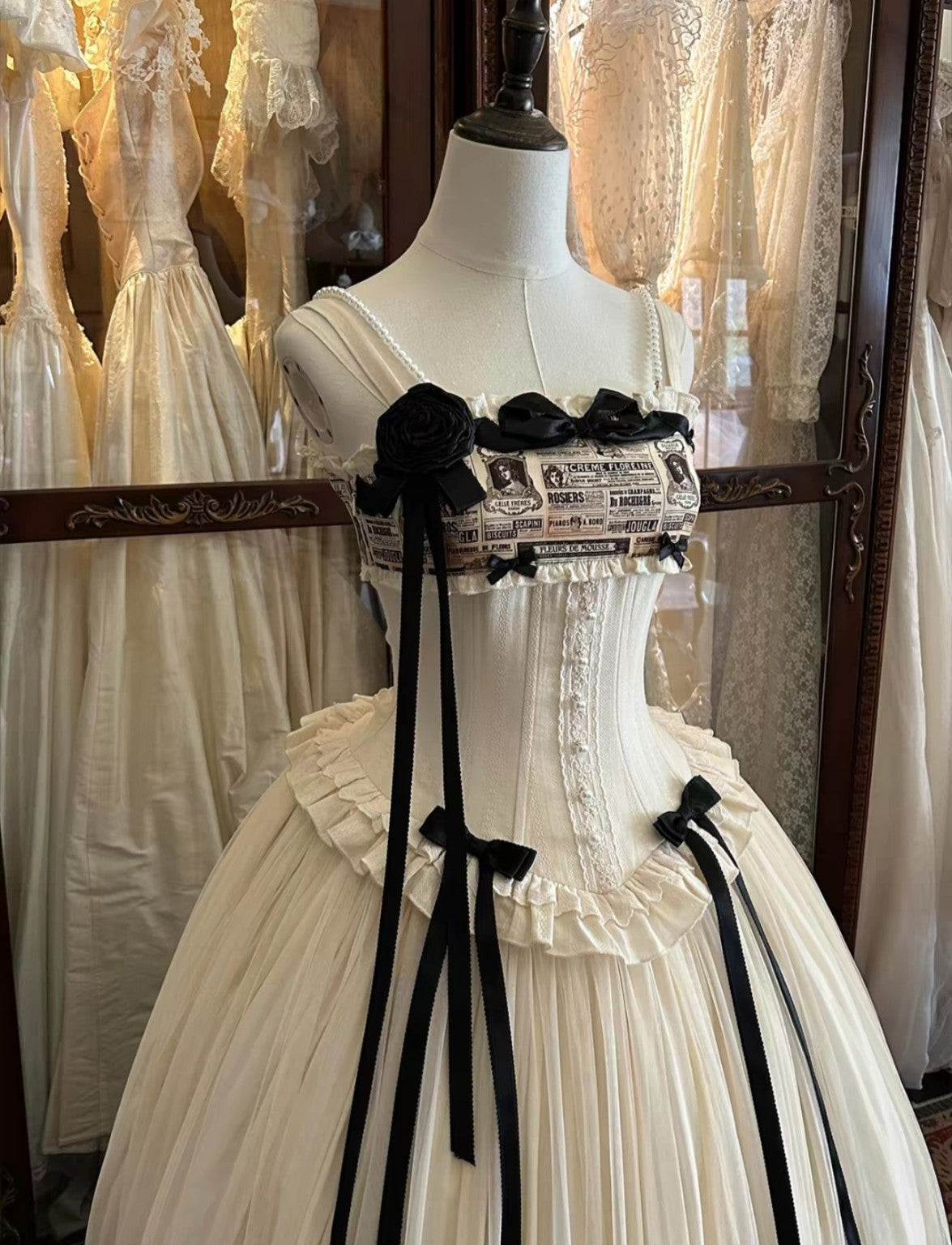Close up cream Lolita bodice with black bows and vintage newspaper print